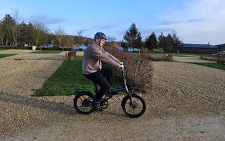 Cyclist riding a folding e-bike on a flat scenic countryside trail in England with open views and smooth paths.
