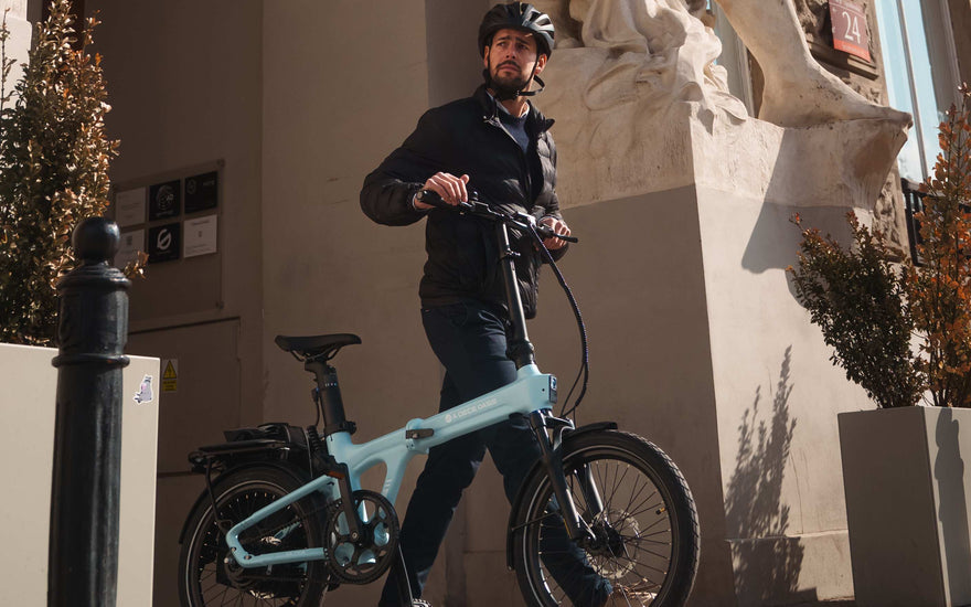 A rider commuting in the UK on a folding electric bike in an urban street environment.